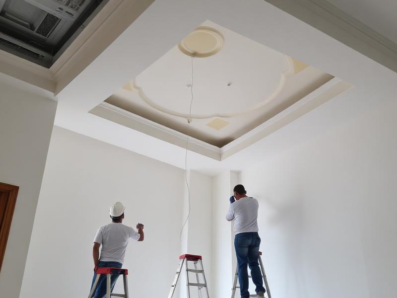 Workers completing ceiling and painting finishes indoors